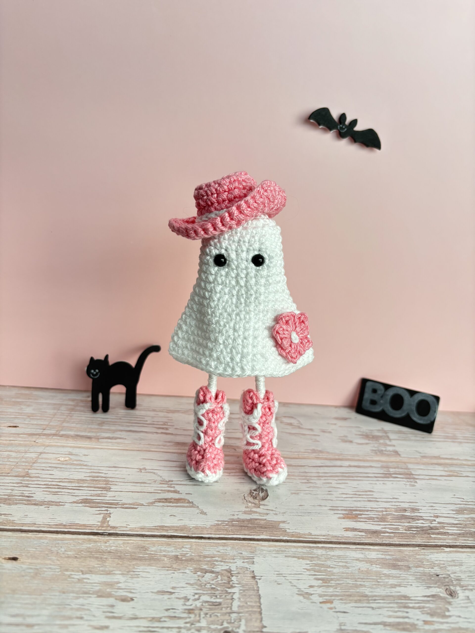 crochet cowgirl ghost with pink hat, boots, and flower on dress
