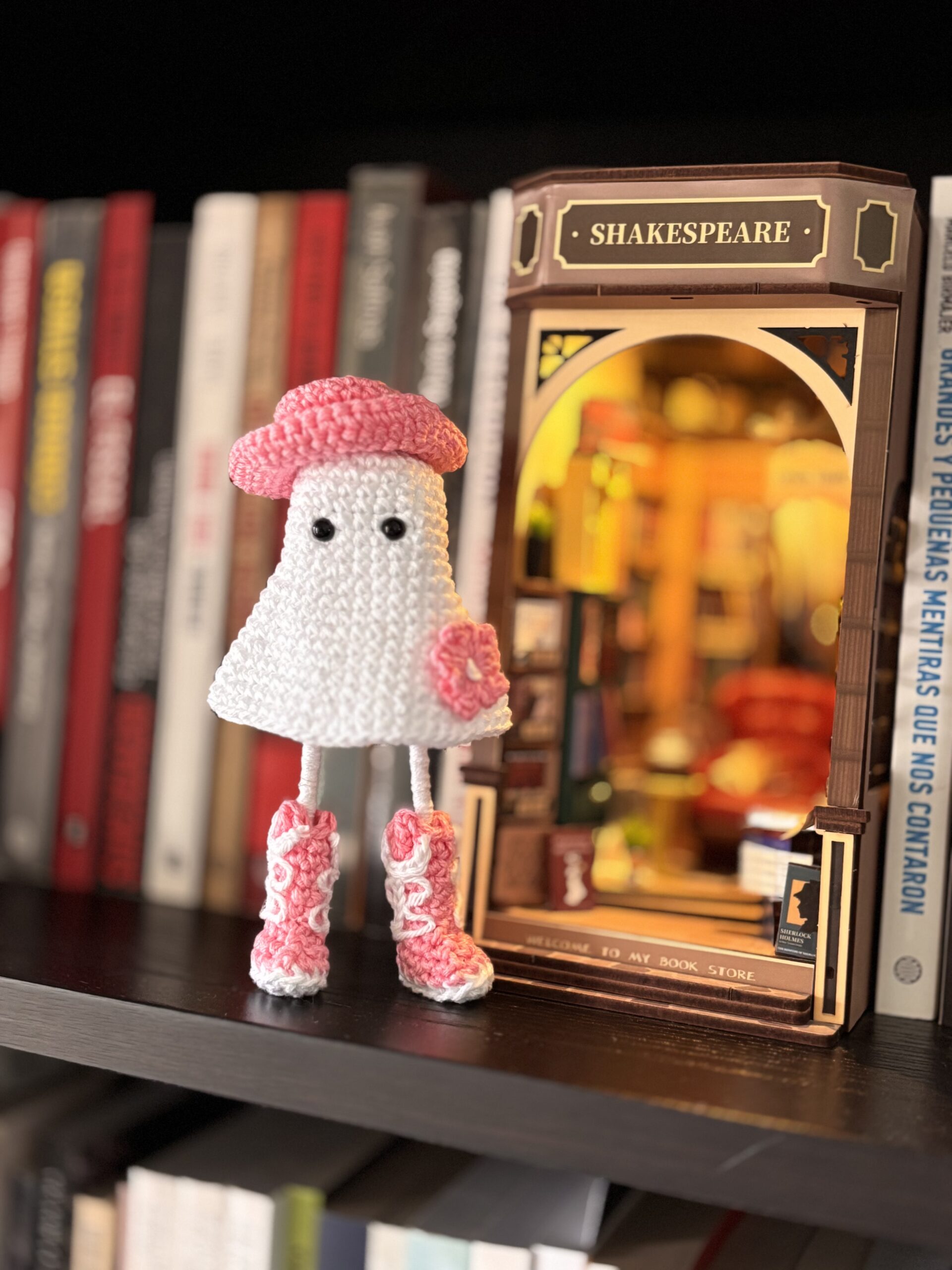 crochet cowgirl ghost with pink boots, hat and flower on a shelf